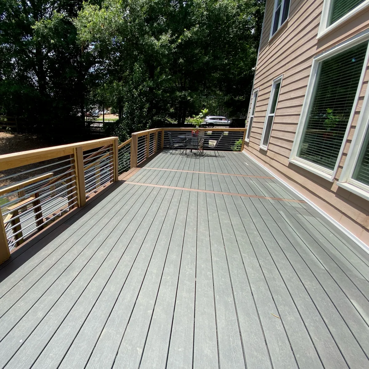 A composite deck with a wood-topped cable railing